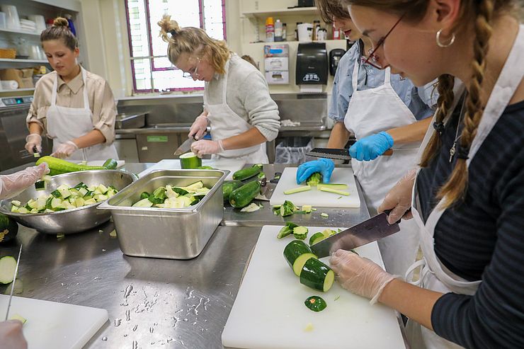 several people in aprons cutting up zucchini