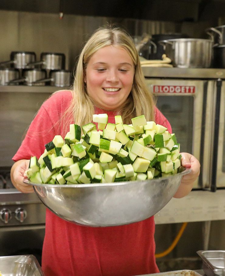 person carrying a large bowl of cut zucchini