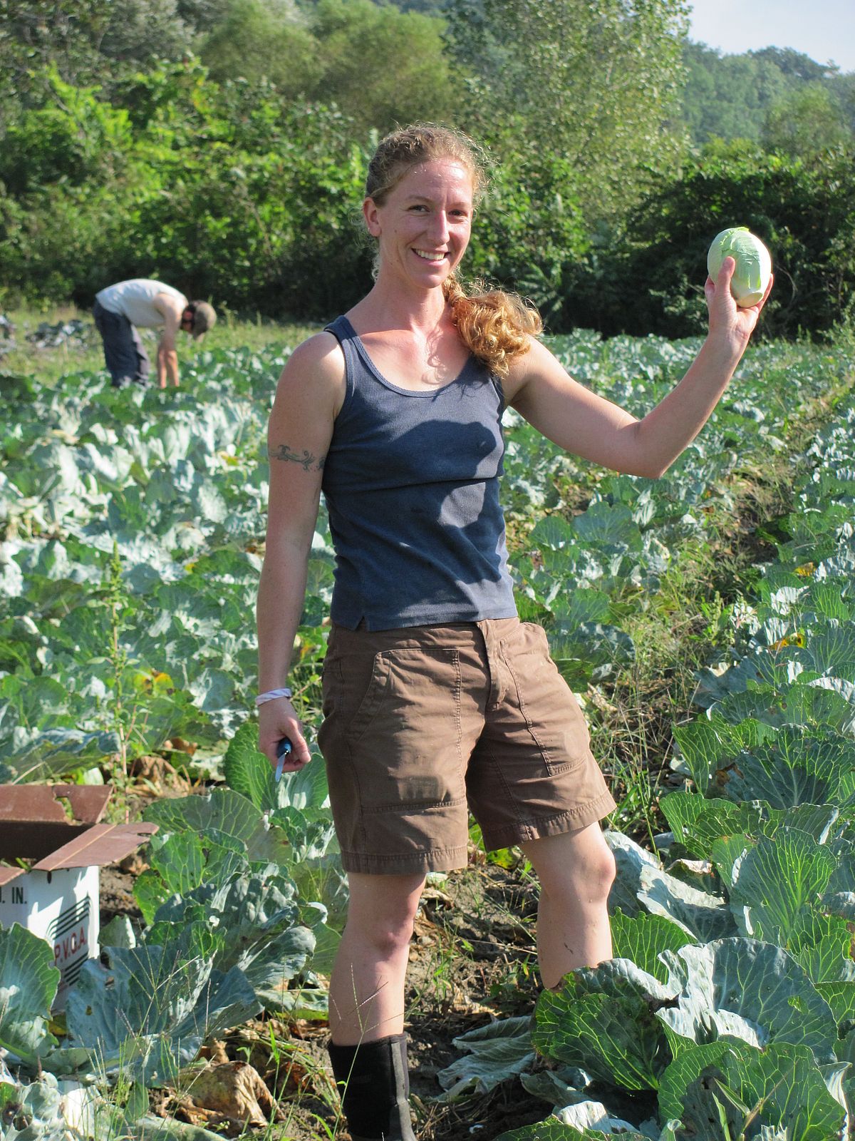 woman stands in field holding turnip