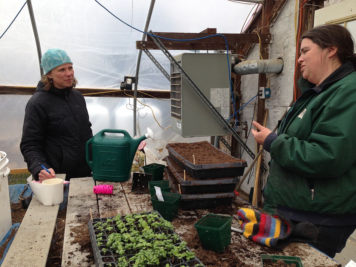 two women chat in a greenhouse