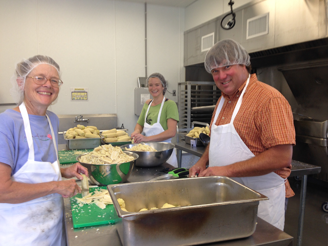 Volunteers process gleaned corn into packets of kernel corn.