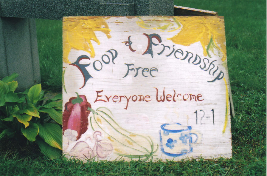 A hand-painted sign reads %22Food & Friendship Free, Everyone Welcome%22